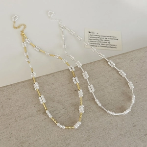Minimalistische parelketting met goud en zilver accenten op linnen achtergrond