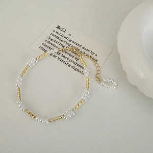 Detail van elegante gouden spiraalbuizen en witte parels aan verstelbare ketting