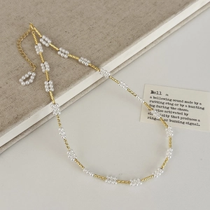 Close-up van elegante goudkleurige parelketting op een beige linnen boekachtergrond