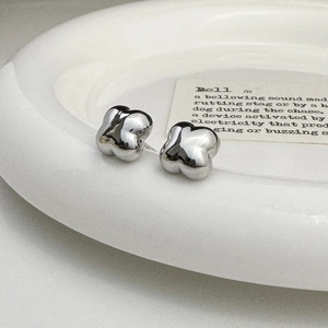 Detailed view of silver clover stud earrings with mirror finish on a white plate