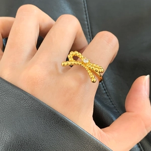 Bague nœud dorée élégante avec perles texturées et zircon sur la main du modèle