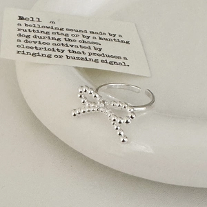 Adjustable silver bow ring with bead texture on a minimalist white ceramic tray