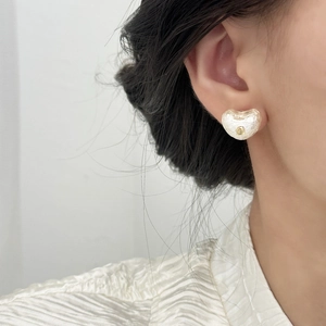 Boucles d'oreilles cœurs perles crème élégantes avec détail doré sur modèle