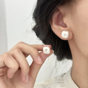 Gros plan sur des boucles d'oreilles carrées en perles de coton blanc mat et or