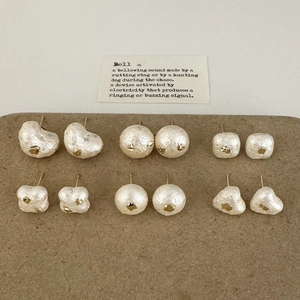 Détail de six paires de boucles d'oreilles en perles blanches avec accents dorés