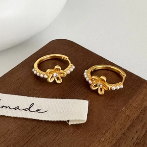 Detailed macro view of gold flower earrings with small pearls and a zircon center