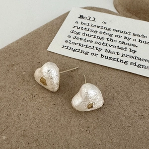 Détail de boucles d'oreilles cœur en perle de coton et feuille d'or sur papier vintage