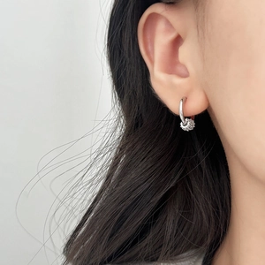 Boucles d'oreilles créoles argentées avec pendentifs sphériques portées par un modèle