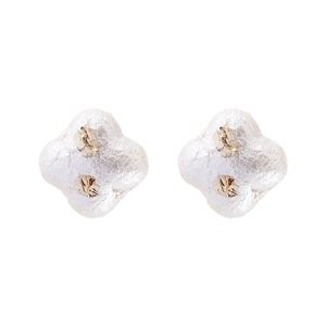 Détail des boucles d'oreilles trèfle avec texture nacre blanche et finitions dorées
