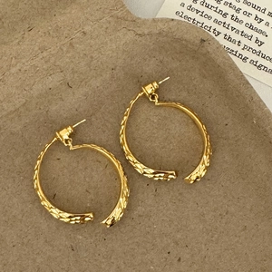 Detailed shot of gold-plated C-shape hoop earrings with textured diamond pattern finish