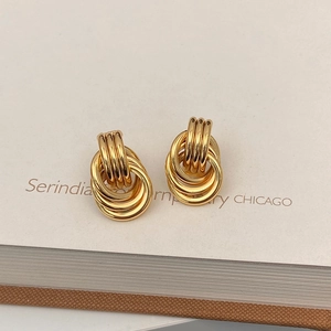 Detailed macro shot of gold-plated multi-layered intertwining hoop earrings on white card