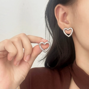 Minimalist silver hollow heart stud earrings showing elegant style on female model