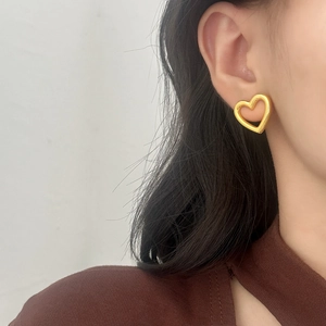 Elegant hollow heart-shaped gold stud earrings worn by a model for a stylish look
