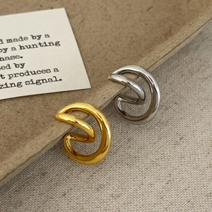 Minimalist crisscross ear cuffs in gold and silver finish on artistic display
