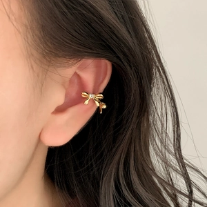 Minimalist gold bow ear cuff with sparkling zircon stone worn on a female ear