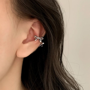 Minimalist silver bow ear cuff with a small center diamond shown on model's ear