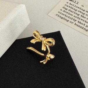 Detail view of a gold bow ear cuff with a clear zircon on a premium black display stand