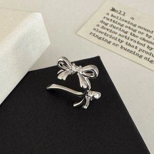 Close-up of a silver bow-shaped ear cuff with a tiny crystal on a vintage background