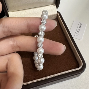 Elegant Shamballa pearl bracelet with sparkling crystal paved beads held against a gift box