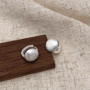 Minimalist silver brushed metal hoop earrings displayed on wood and linen background