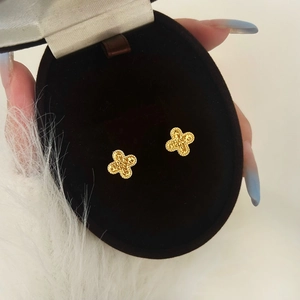 Detailed macro view of gold-toned clover stud earrings with embossed texture