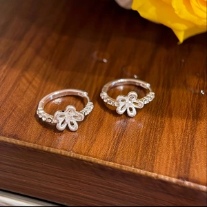 Elegante Blumencreolen aus Silber mit Zirkon-Kristallen auf dunklem Holzhintergrund