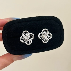 Macro shot of silver hollow clover stud earrings with sparkling zircon crystals