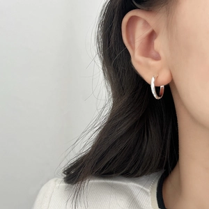 Créoles argentées minimalistes avec texture martelée irrégulière sur l'oreille
