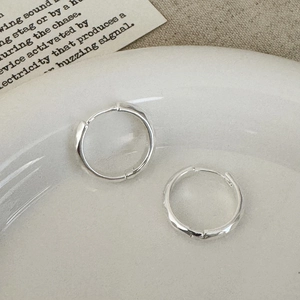 Détail de créoles en argent avec une texture martelée à la main et un design ondulé