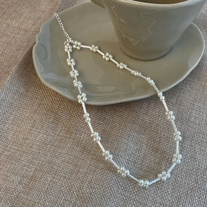 Elegante Silberkette mit Perlenblumen-Akzenten auf einer Keramiktasse präsentiert