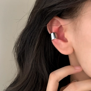 Minimalist wide band ear cuff in polished silver finish worn on the ear cartilage