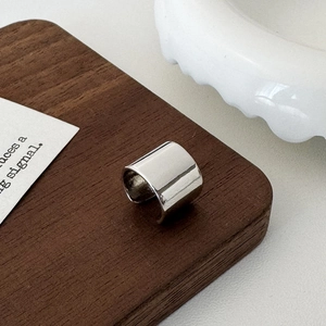 Close-up of a wide polished silver ear cuff with a sleek C-shaped minimalist design