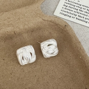 Macro detail of square woven texture silver stud earrings on a minimalist background