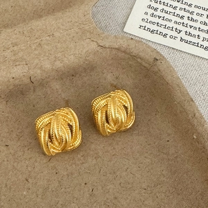 Close-up of vintage golden matte earrings with woven texture and square curved edges