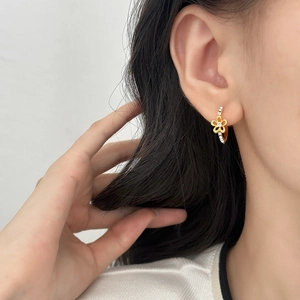 Minimalist gold hollow flower hoop earrings with zircon stones worn on the ear