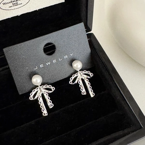 Detail of bow earrings with pearls displayed on a premium black velvet jewelry box