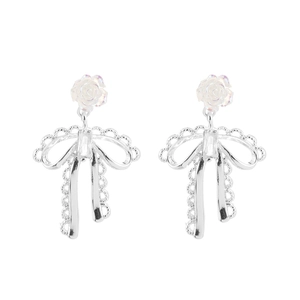 Detail of silver bow earrings with frosted rose and lace-edged hollow metal patterns