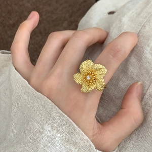 Eleganter Goldring in Blumenform mit Hammerschlag-Textur und Kristall auf Hand