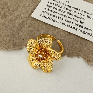 Detailaufnahme goldener Blumenring mit strukturierten Blütenblättern und Zirkon-Besatz