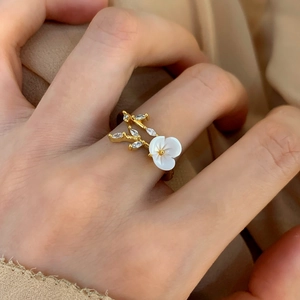 Elegant gold flower ring with white shell petals and marquise zircon leaves on model hand