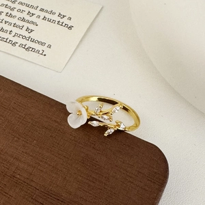 Detail of gold shell flower ring with zircon leaves on vintage wood display