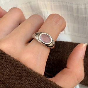 Detail of retro silver ring with oval pink cat eye stone on a model's hand