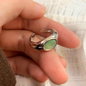 Close-up of retro silver open ring featuring an oval green gemstone worn on a hand