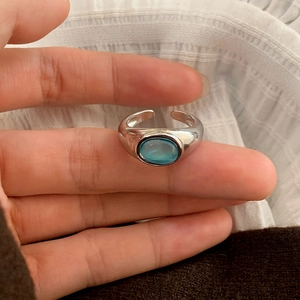 Macro detail of silver adjustable ring featuring a polished band and light blue oval stone
