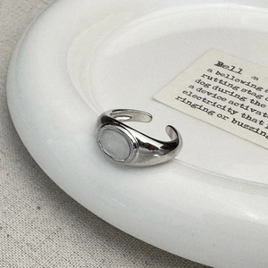 Detailed view of an oval signet open ring with polished silver finish on ceramic tray