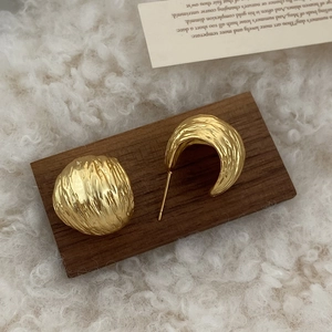 French vintage gold earrings with irregular hammered texture on dark wood background