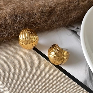Close-up of French vintage gold stud earrings with irregular crumpled texture finish