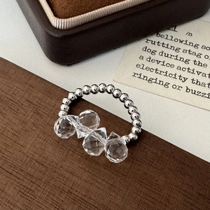Detail shot of beaded silver ring with four faceted transparent crystals on vintage paper