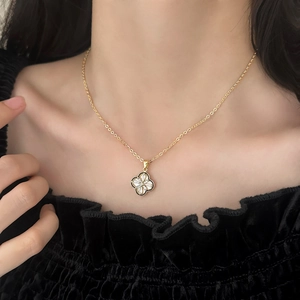 Elegant gold clover necklace with black enamel and crystals worn by a model
