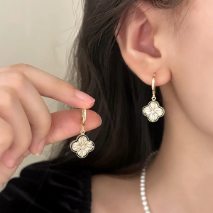 Detailed view of gold clover earrings with black enamel and sparkling zircon centers